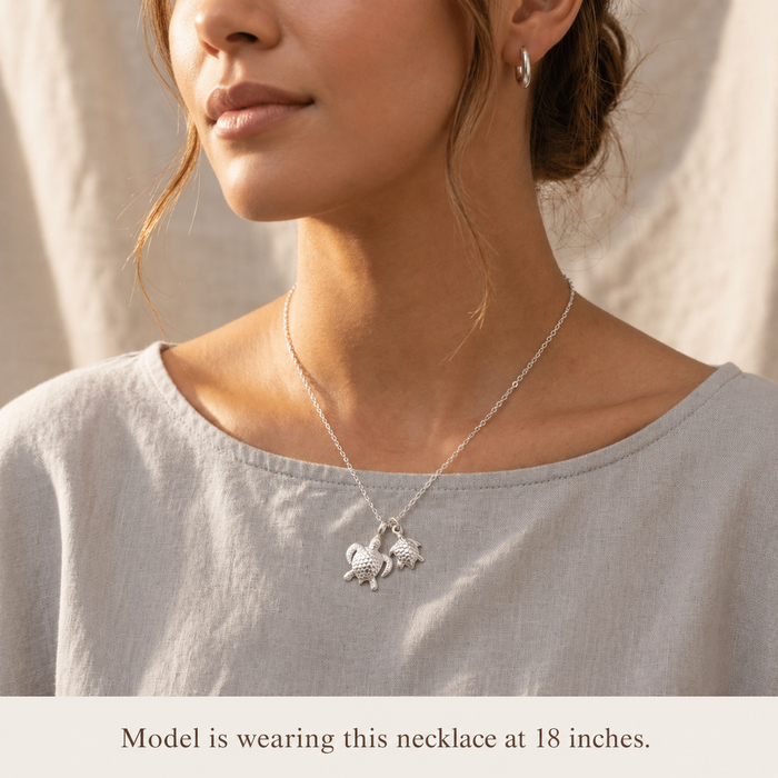 Model wearing a sterling silver mama and baby turtle necklace at 18 inches, delicate sea turtle jewelry for everyday wear.