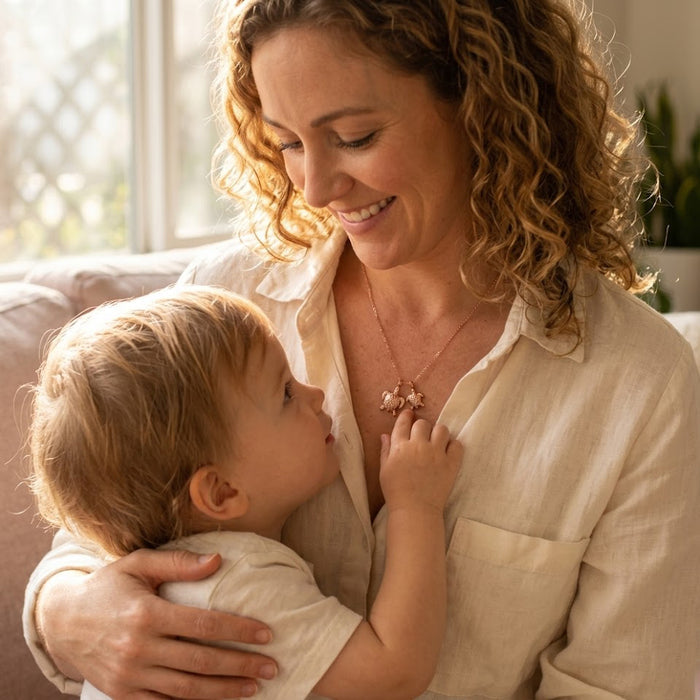 New mom wearing a mama and baby turtle necklace while holding her baby, meaningful mother and child keepsake jewelry.