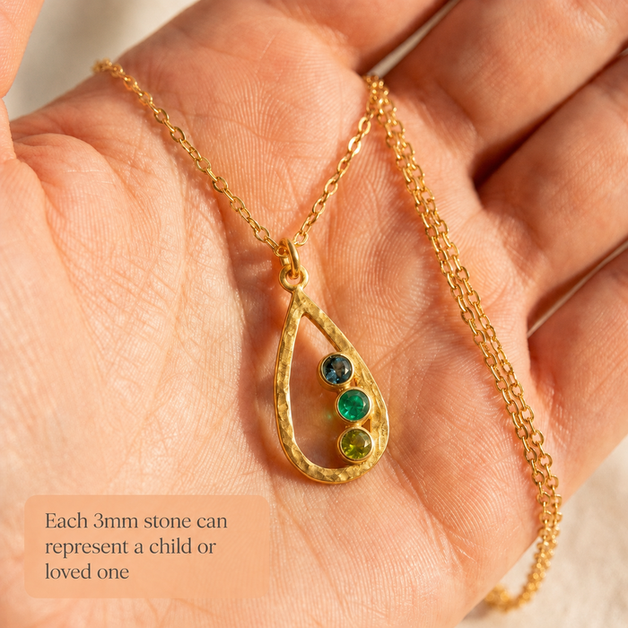 Close-up of custom teardrop birthstone necklace in hand, showing each small stone can represent a child or loved one.