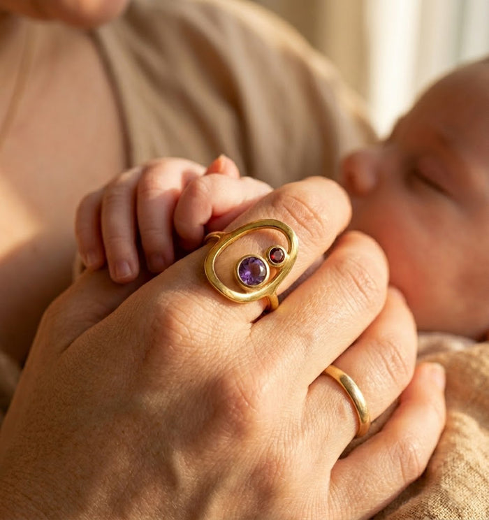 New mom wearing personalized mother child birthstone ring while holding baby’s hand.
