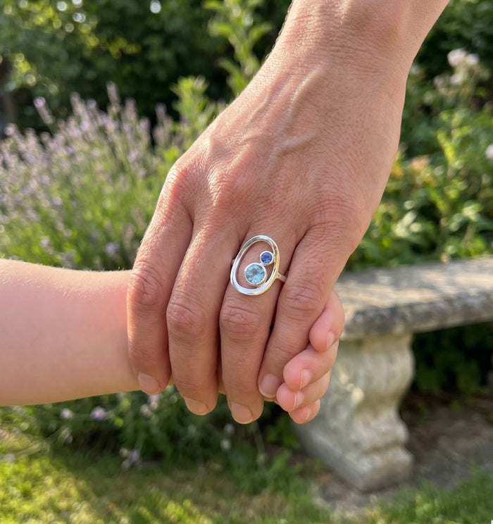 New mom wearing personalized mother child birthstone ring while holding baby’s hand