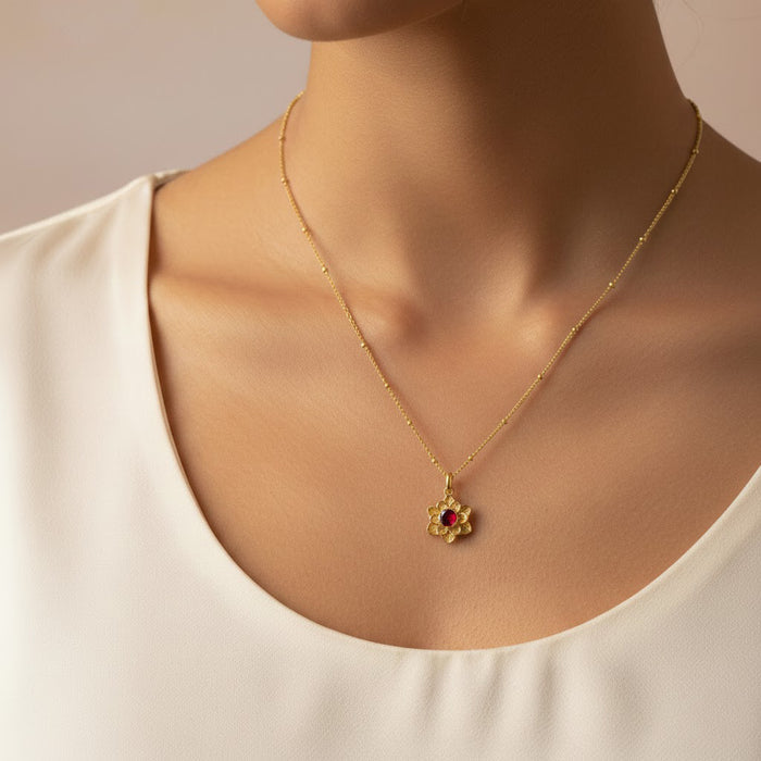 gold birthstone flower necklace worn by woman on delicate gold beaded chain, small bloom pendant with rich red center stone resembling a garnet, elegant minimalist jewelry that sits perfectly at the collarbone, personalized birthstone flower necklace option in sterling silver or gold filled, meaningful gift for her for birthday, Mother’s Day, anniversary or Christmas, dainty bloom pendant ideal for everyday wear or layering with other necklaces