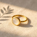 Oval mother of pearl cabochon ring in yellow gold vermeil on a soft neutral background with warm natural light.