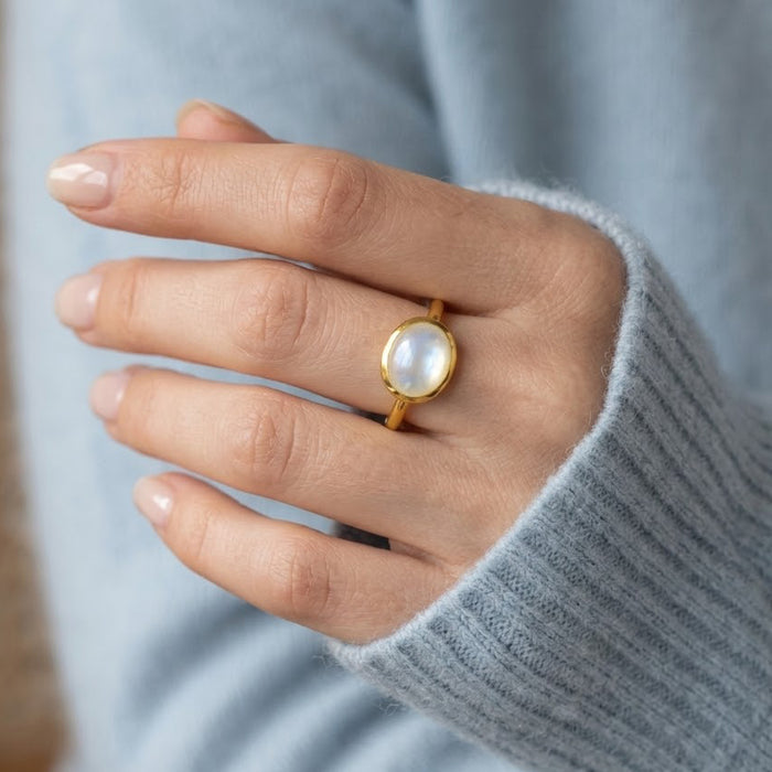 Mother of pearl oval gemstone ring worn on hand with a cozy sweater, shown as a minimalist everyday gold ring.