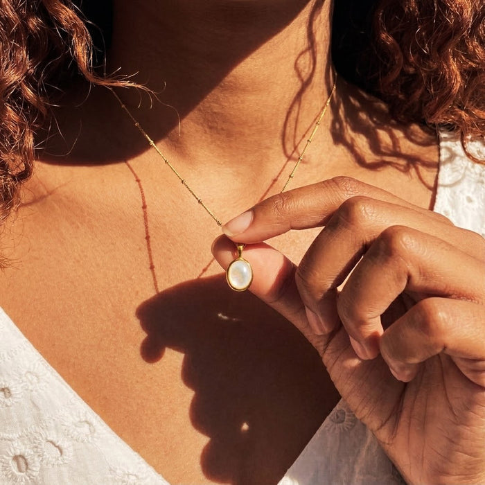Model wearing a dainty Mother of Pearl necklace, shown close up as an everyday June birthstone pendant.