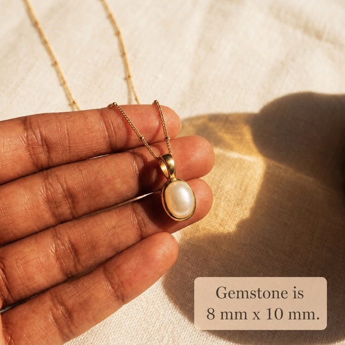 Gold Mother of Pearl oval necklace held in hand, showing the 8 x 10 mm gemstone size.