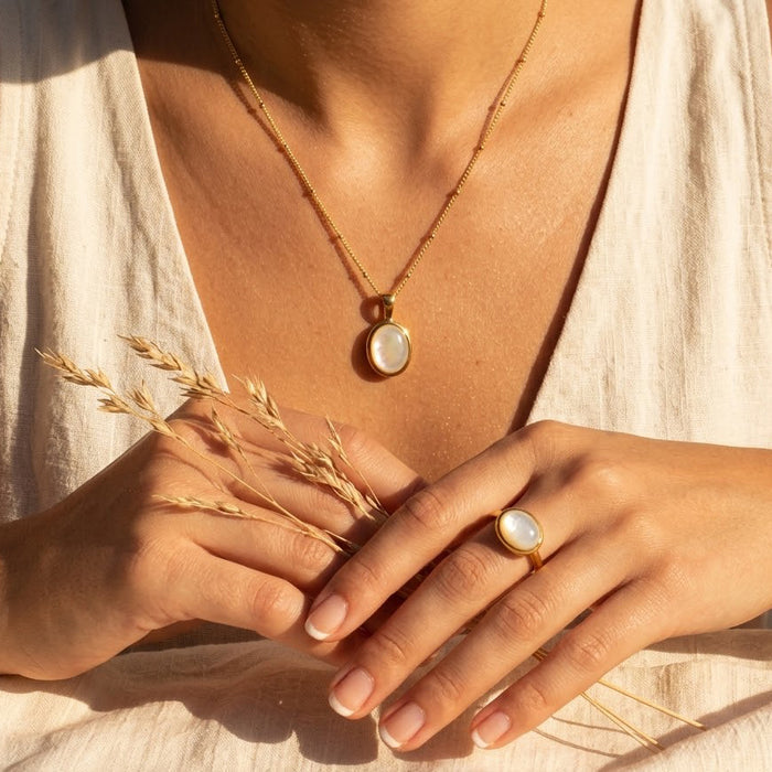 Mother of Pearl necklace and matching ring worn by a model in warm sunlight.