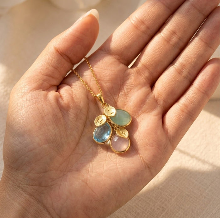 Custom birthstone necklace held in hand, showing cascading teardrop gemstones and initial charms for personalized mother’s jewelry.