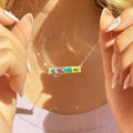 Multi birthstone bar necklace for mom shown on model in warm sunlight with colorful rectangular stones.