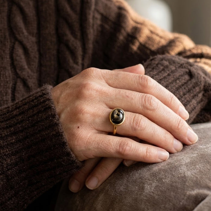 Black obsidian oval ring worn on hand with cozy sweater as everyday gemstone jewelry