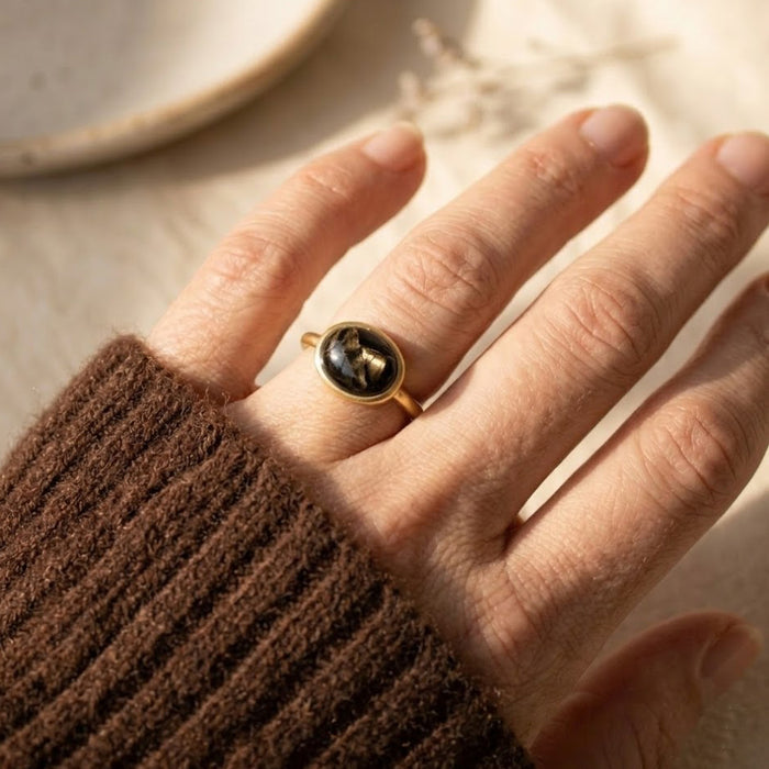 Model wearing black obsidian gemstone ring with gold bezel setting on hand