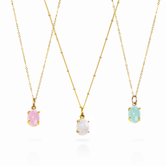 Three vertical prong-set oval cabochon birthstone pendants in yellow gold, rose gold, and bright sterling silver colors, displayed on matching gold-filled chains.