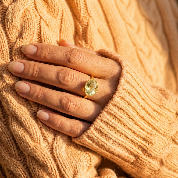 Model wearing a lemon quartz oval ring with a soft peach sweater, showing the yellow gemstone ring styled on hand.