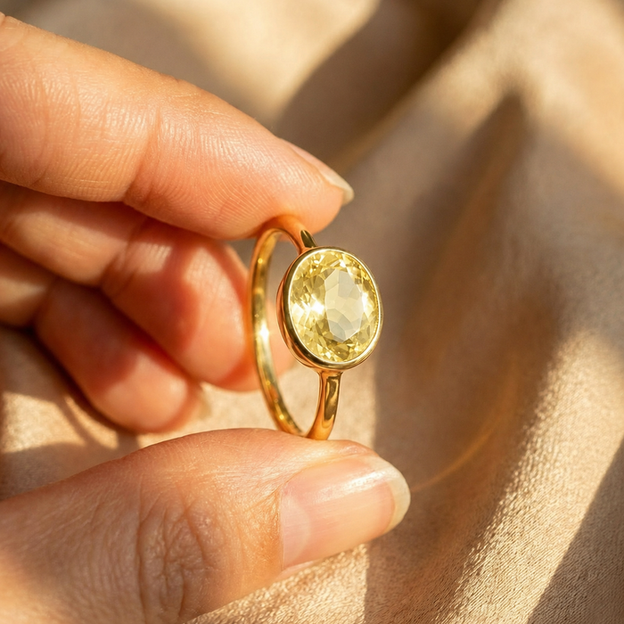 Lemon quartz ring paired with another gemstone ring on a green sweater, showing how the oval ring looks when stacked.
