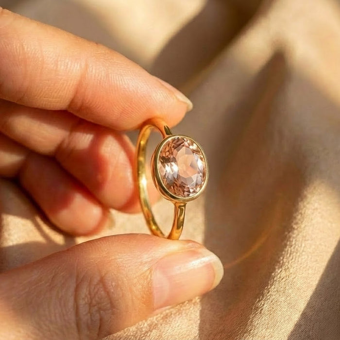 Close-up of oval morganite bezel ring, blush pink gemstone in gold setting