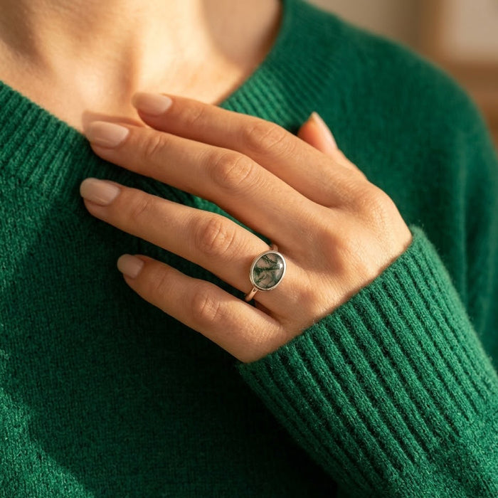 Moss agate ring worn with green sweater, showing the oval gemstone ring in a nature-inspired everyday look.