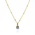 Oval natural tanzanite Cabochon Bezel Set into a 925 Sterling Silver Pendant Plated in 18k Vermeil Gold sitting on a 14K Gold Filled Cable Chain resting on a white background. Great as a gift for fall lovers and sophisticated blue color and sunstone lovers.