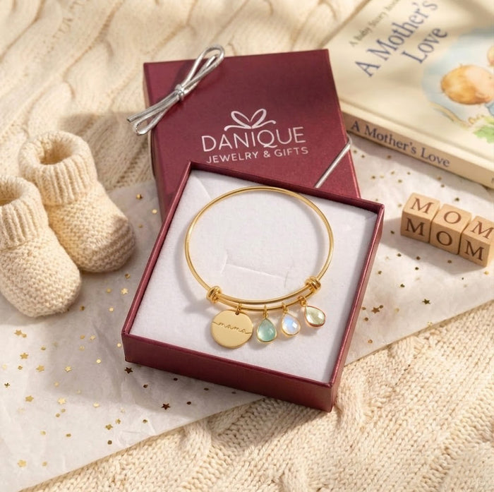 Gold custom birthstone bangle bracelet with engraved family charm, designed as a sentimental Mother’s Day or grandmother gift.