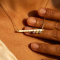 Personalized birthstone bar necklace with three gemstones and engraved initials worn on model