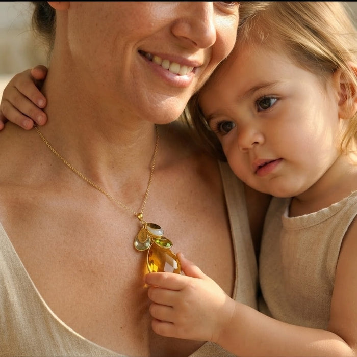 Mother wearing personalized birthstone necklace while holding her young child