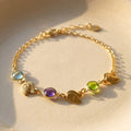 Custom birthstone and initial bracelet for mom with engraved double leaf charms in gold on neutral background