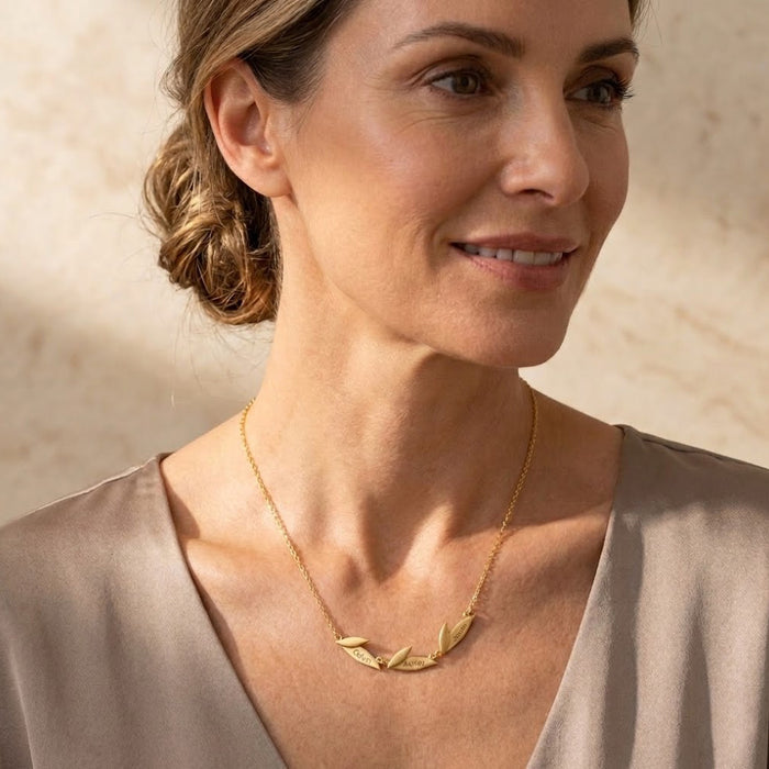 Woman wearing a personalized leaf necklace with name charms, a delicate custom necklace for mom, grandma, or family jewelry gift.