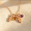 Personalized mom necklace with two engraved child charms and birthstone pendants on a rose gold chain.
