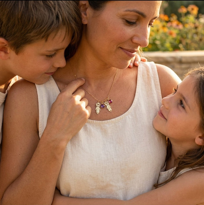 Mother wearing a custom kids name necklace with birthstones while holding her children.