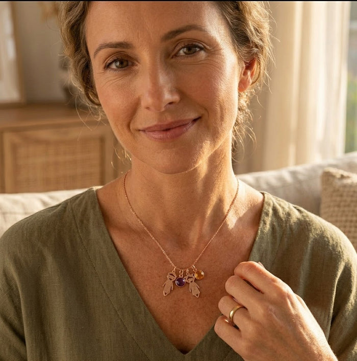 Mom holding her child while wearing a personalized children’s charm necklace with engraved names.