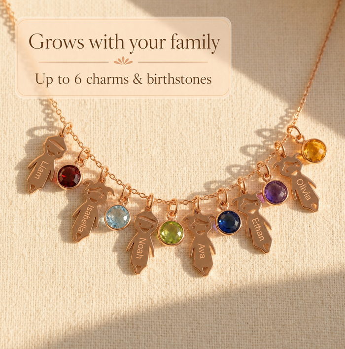 Family necklace with up to six child charms and birthstones shown on warm neutral fabric.