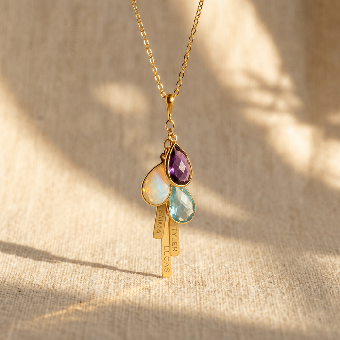 Personalized mom birthstone necklace with engraved vertical name bar charms on a warm neutral background.