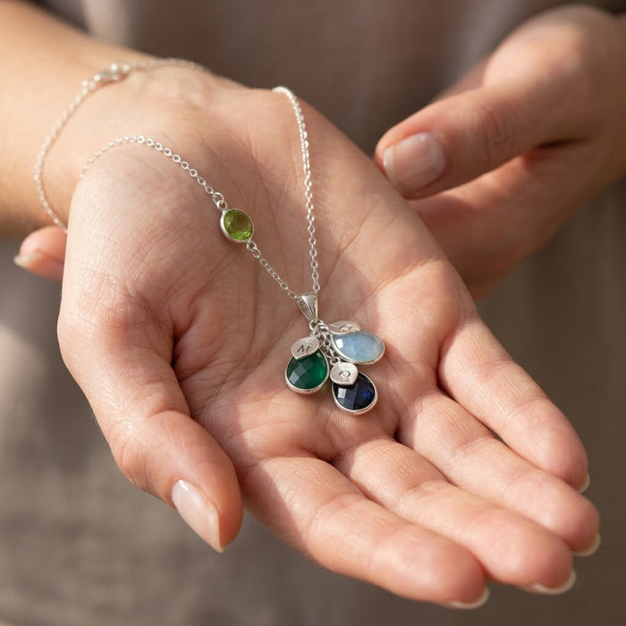Custom family birthstone necklace held in hands, a meaningful mom or grandma necklace with birthstones and engraved initials.