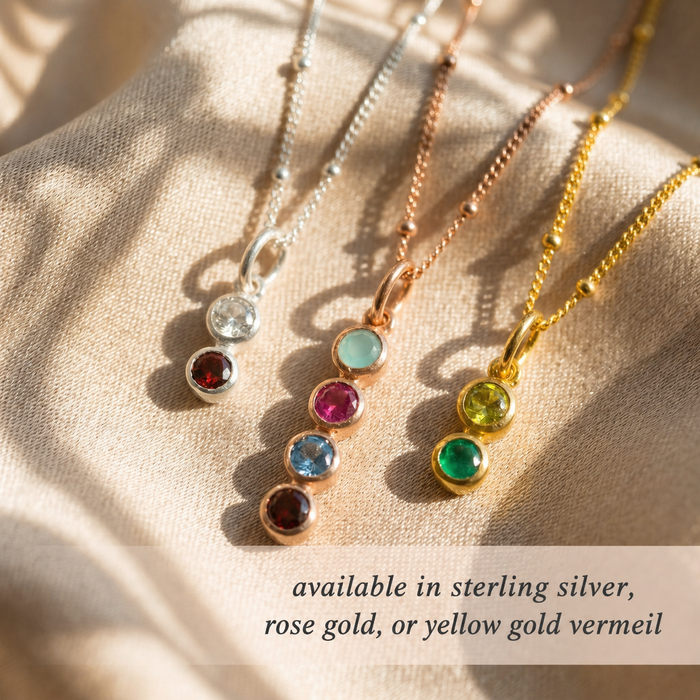Three necklaces with colored gemstones on a beige fabric background. Each necklace is crafted with 925 sterling silver, 18k rose gold vermeil, or 18k yellow gold vermeil.
