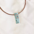Rose gold wire chain with rectangular flower pendant on beige background. Dainty flower designs, statement necklace, statement earrings, bohemian necklace, bohemian jewelry