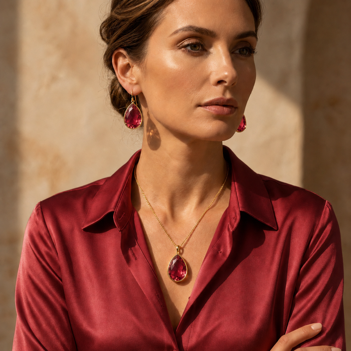 Model wearing ruby quartz pendant necklace with a ruby red blouse and matching ruby earrings.