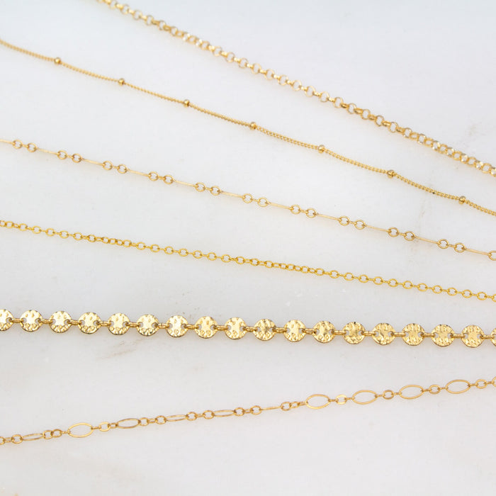 Detailed view of the gold filled rolo, satellite, box, cable, coin and loop anklets.