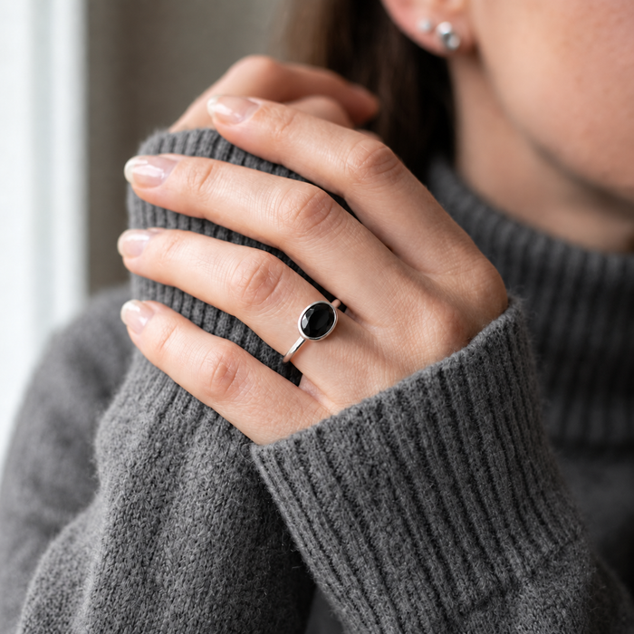 Dainty black onyx stacking ring worn with oval gemstone rings on hand