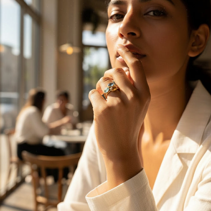 Lifestyle photo of a woman wearing a small oval green amethyst ring in a warm café setting, showcasing a bezel-set prasiolite gemstone in a minimalist gold vermeil design. Elegant February birthstone ring styled for everyday wear, stacking, and modern fashion. Handcrafted gemstone jewelry designed for meaningful gifting, anniversaries, birthdays, or Valentine’s Day, highlighting timeless style, feminine elegance, and effortless sophistication.
