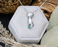 Silver hand pendant with a raw emerald in a hexagonal jewelry box.