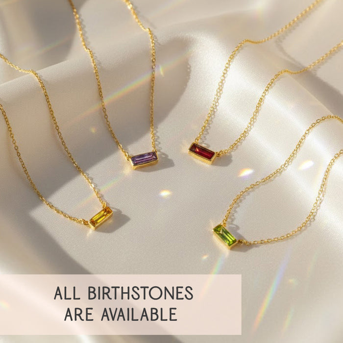 tiny adira birthstone bar necklaces displayed on soft champagne satin with rainbow light reflections, four dainty gold vermeil chains each featuring a petite horizontal gemstone bar in yellow, purple, red and green, showcasing the minimalist design and rich color options, text reading all birthstones are available emphasizes that every month’s gemstone can be chosen, making this personalized bar necklace a perfect birthday, bridesmaid, graduation or everyday gift