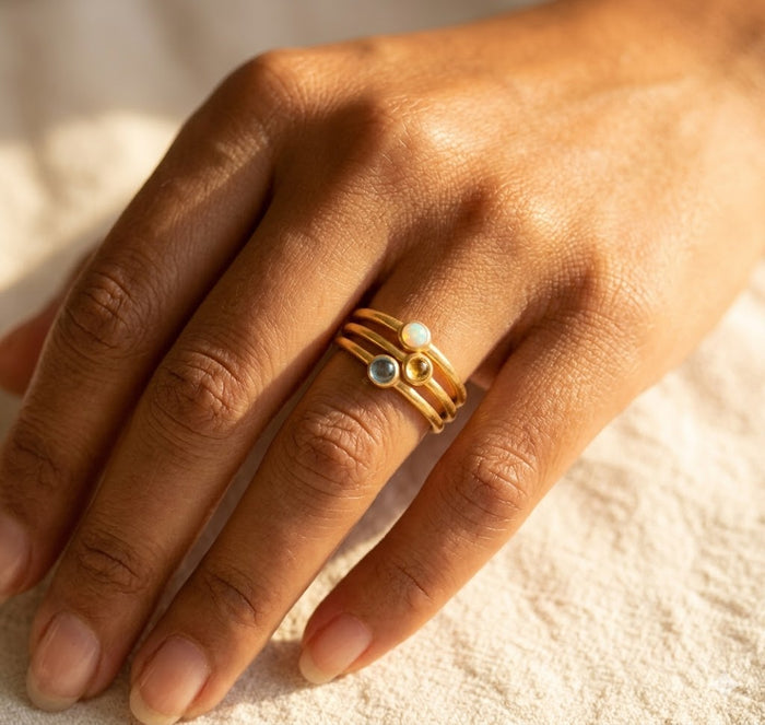 Custom tiny birthstone ring worn on hand, a delicate gold stacking ring personalized with a customer’s chosen cabochon gemstone.