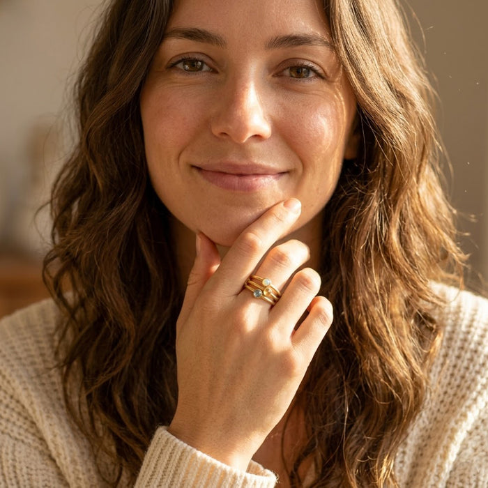 Woman wearing tiny birthstone stacking ring in gold, a delicate personalized jewelry gift for mom, sister, bridesmaid, or friend.
