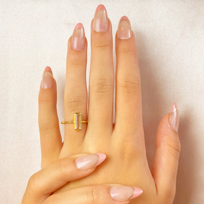Hand wearing clear quartz bar ring, minimalist gold crystal stacking ring for women