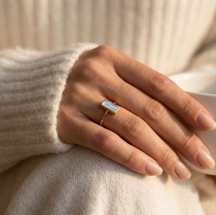Model wearing tiny moonstone baguette ring as a dainty June birthstone stacking ring.