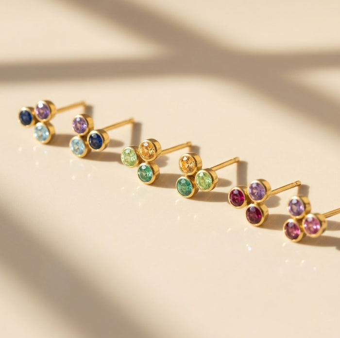 Custom birthstone stud earrings arranged on neutral fabric, perfect for choosing three children’s birthstones or family stones.