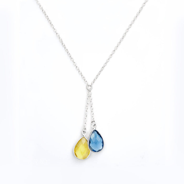 Minimalist lariat birthstone necklace in bright sterling silver showing two faceted teardrops—sky blue and golden yellow—set in bezel frames. Modern, elegant support-Ukraine pendant designed for everyday wear or layered looks. Adjustable chain with delicate profile makes a thoughtful solidarity gift for friends and family. Keywords: necklace ukraine, teardrop birthstone, sterling silver necklace, blue and yellow pendant, dainty layered necklace.