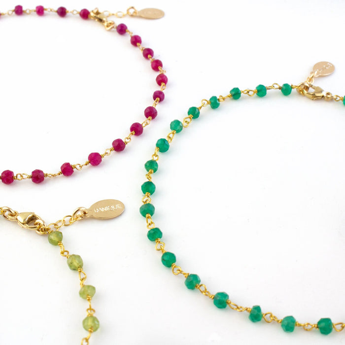 Detailed view of the gold filled anklet trio with ruby, green onyx and peridot gemstones.